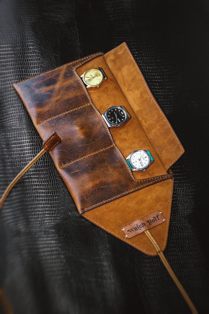 about-bg Stylish leather watch roll showcasing three elegant timepieces for travel or display.