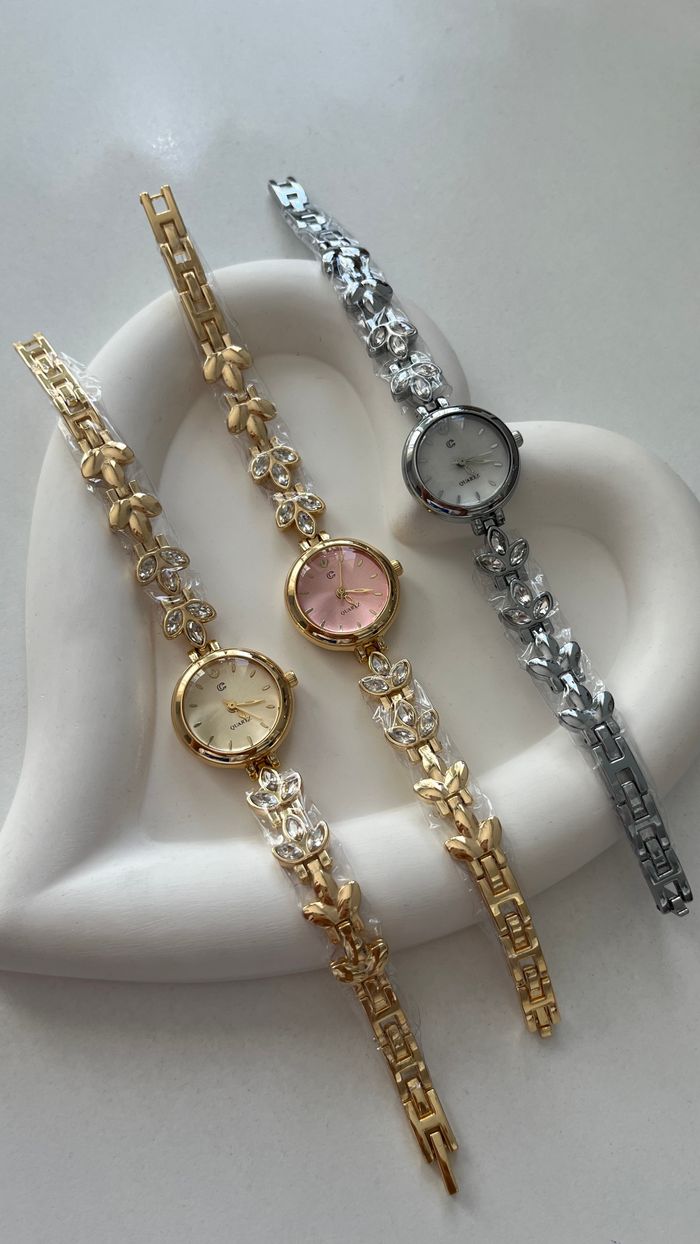 Three elegant gold and silver watches displayed on a heart-shaped holder, showcasing luxury and style.