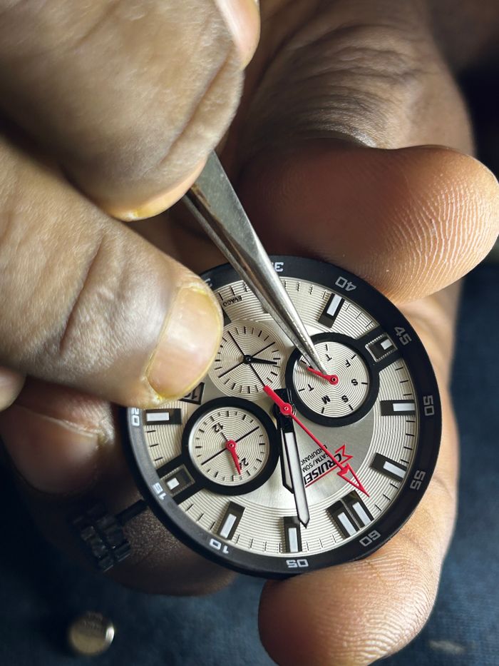 Detailed close-up of a watch repair showing precise work with hands and tools.