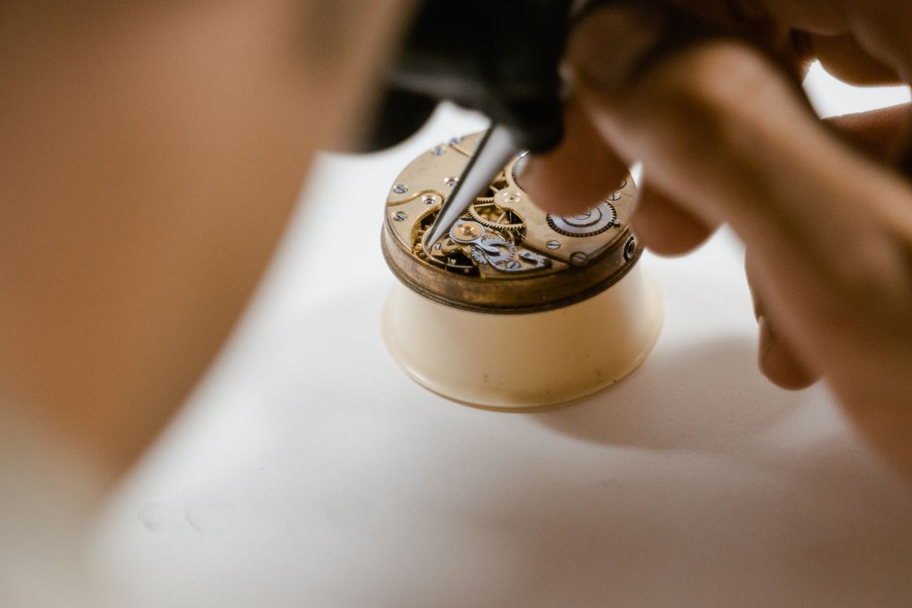 who-we-are Detailed image of a technician repairing a vintage watch mechanism with precision tools.